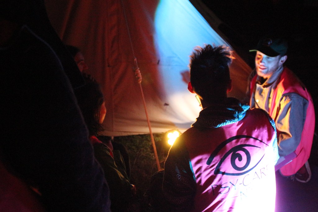 Two Psy-Care volunteers working on site,. It's night, and their pink hi vis vests show up brightly.